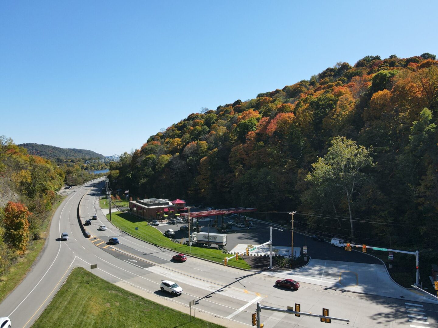 Road intersection near forested hillside in autumn.